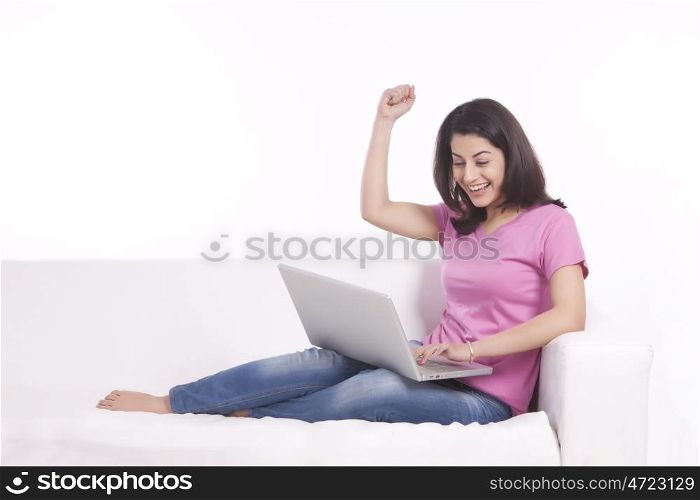 Woman rejoicing while working on laptop