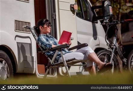 Woman relaxes and reads a book near the camping. Caravan car Vacation. Family vacation travel, holiday trip in motorhome RV.