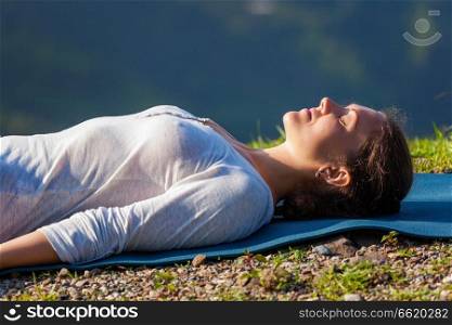 Woman relaxes in yoga relaxation asana Savasana - corpse pose outdoors in Himalayas. Himachal Pradesh, India. Woman relaxes in yoga asana Savasana outdoors