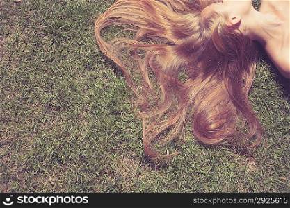 Woman relaxes on the grass. Cute young female lying on grass field at the park.