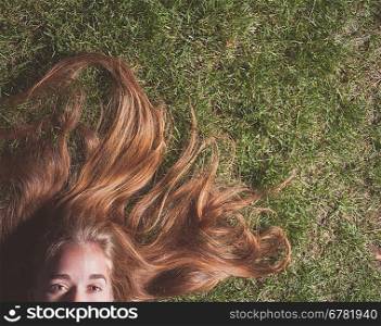 Woman relaxes on the grass. Cute young female lying on grass field at the park.