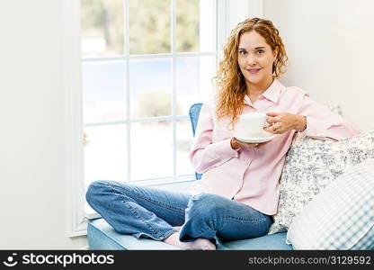 Woman relaxing by the window with beverage