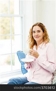 Woman relaxing by the window with coffee