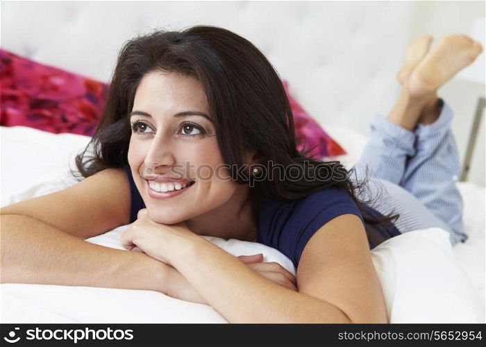 Woman Relaxing In Bed Wearing Pajamas