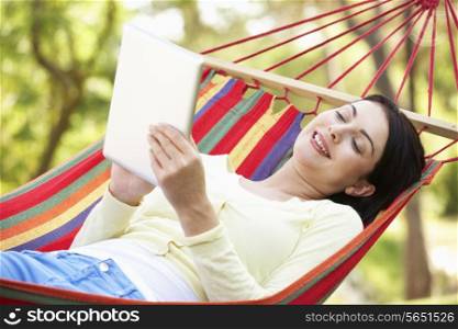 Woman Relaxing In Hammock With E-Book