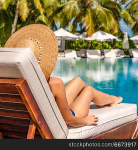 Woman relaxing in lounger at the poolside . Woman relaxing at the poolside