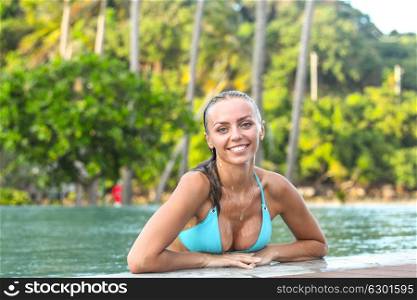 Woman relaxing in swimming pool. Beautiful sexy woman in bikini relaxing in swimming pool at luxury tropical resort