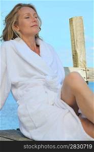 Woman relaxing in the sunshine in a towelling robe