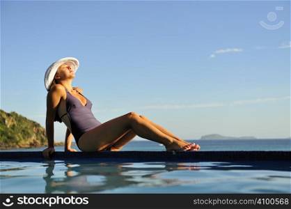 Woman relaxing on a swimming pool with a sea view