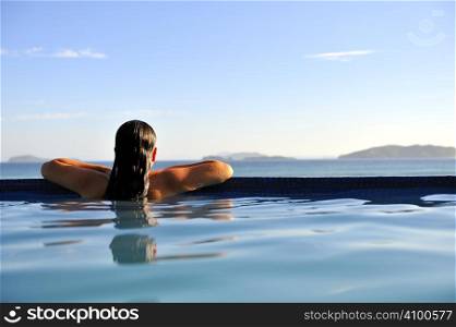 Woman relaxing on a swimming pool with a sea view