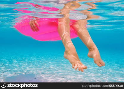 Woman relaxing on inflatable mattress at the beach, view from underwater