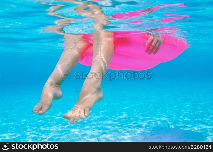 Woman relaxing on inflatable mattress at the beach, view from underwater