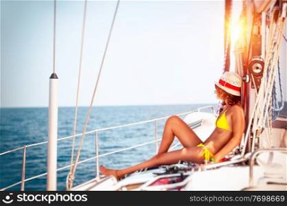 Woman relaxing on sailboat, slim model tanning on the deck of the yacht in bright sunny day, enjoying sailing adventures, luxury summer vacation