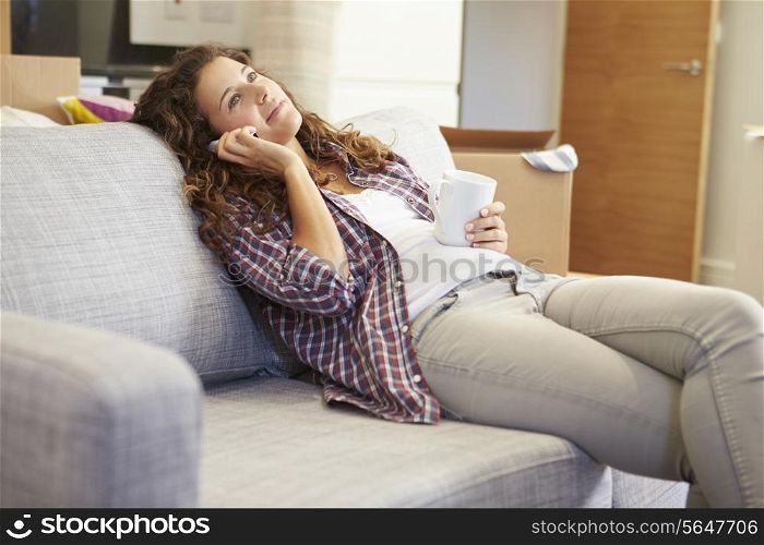 Woman Relaxing On Sofa Talking On Phone In New Home
