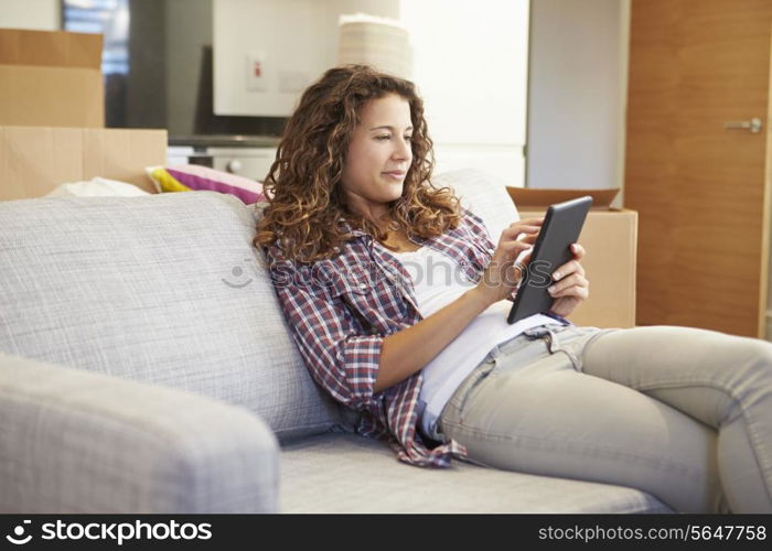 Woman Relaxing On Sofa With Digital Tablet In New Home