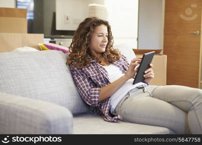 Woman Relaxing On Sofa With Digital Tablet In New Home