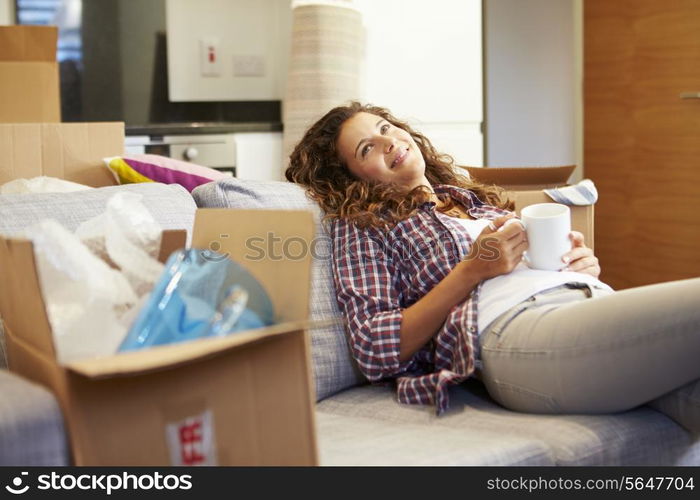 Woman Relaxing On Sofa With Hot Drink In New Home