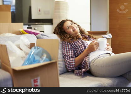 Woman Relaxing On Sofa With Hot Drink In New Home