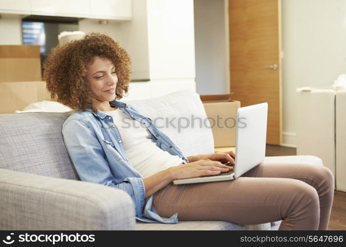 Woman Relaxing On Sofa With Laptop In New Home
