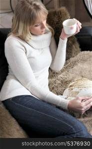 Woman relaxing on sofa with mug of coffee