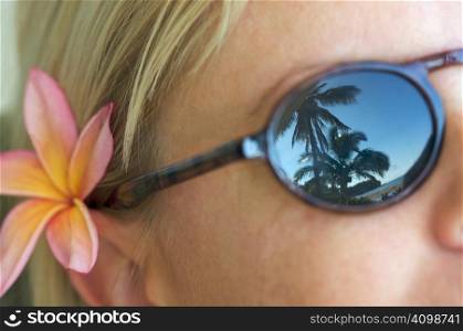 Woman Relaxing while Sunglasses Reflect Palm Trees and Shorline.