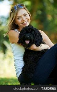 woman relaxing with black dog while on a walk in the park