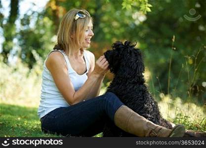 woman relaxing with black dog while on a walk in the park