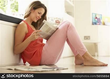 Woman Relaxing With Newspaper At Home