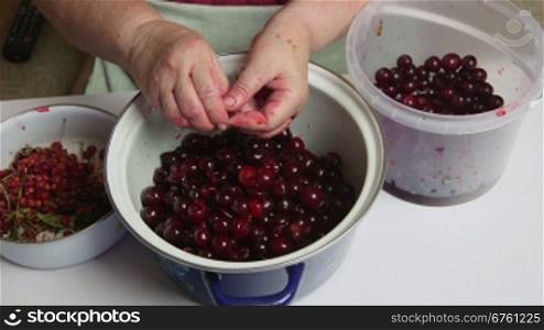 Woman removes the pits from cherries for cooking cherry jam