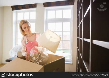 Woman removing lamp from cardboard box at new home