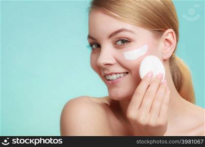 Woman removing makeup with cotton swab pad from face. Young girl taking care of skin. Skincare concept. Studio shot on blue. Woman removing makeup with cream and cotton pad