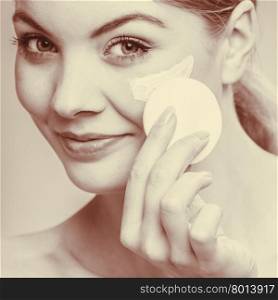 Woman removing makeup with cream and cotton pad. Woman removing makeup with cotton swab pad from face. Young girl taking care of skin. Skincare concept. Sepia tone
