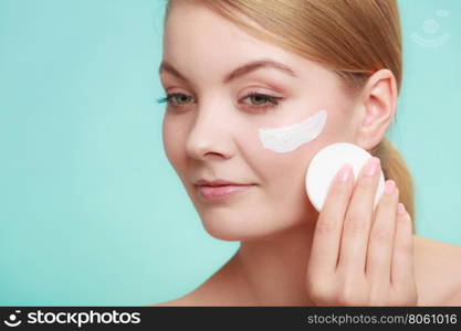 Woman removing makeup with cream and cotton pad. Woman removing makeup with cotton swab pad from face. Young girl taking care of skin. Skincare concept. Studio shot on blue