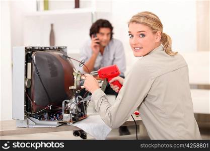 Woman repairing television with soldering iron