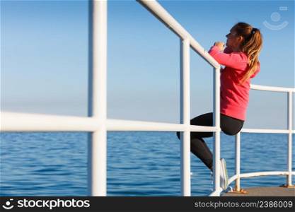 Woman resting after doing sports outdoors. Fitness girl in sportswear sitting on pier relaxing looking at horizon back view. Woman sitting on pier looking at horizon outdoors