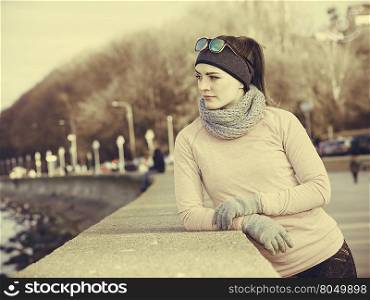 Woman resting after doing sports outdoors on cold day. Woman resting relaxing after doing sports outdoors. Fitness girl female jogger wearing warm sporty clothes in cold day weather on seaside taking break