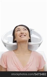 Woman resting head in sink against white background