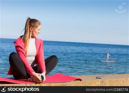 Woman resting relaxing after doing sports outdoors. Fitness girl female in sportswear on seaside takes break. Woman resting relaxing after doing sports outdoors