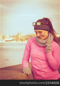 Woman resting relaxing after doing sports outdoors. Fitness girl female jogger wearing warm sporty clothes in cold day weather on seaside taking break. Woman resting after doing sports outdoors on cold day