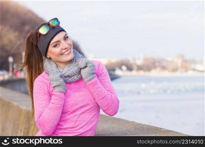 Woman resting relaxing after doing sports outdoors. Fitness girl female jogger wearing warm sporty clothes in cold day weather on seaside taking break. Woman resting after doing sports outdoors on cold day