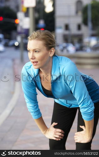 Woman Resting Whilst Running Along Urban Street