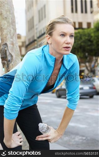 Woman Resting Whilst Running Along Urban Street