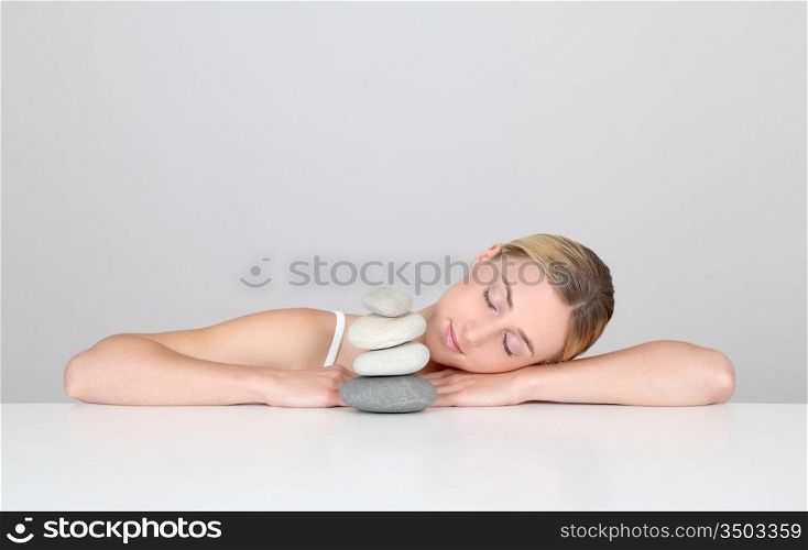 Woman resting with eyes shut by pile of pebbles