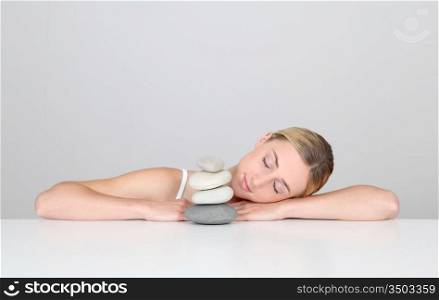 Woman resting with eyes shut by pile of pebbles