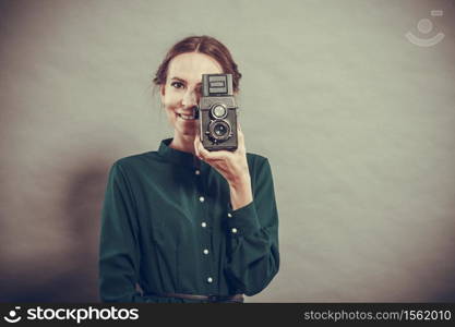 Woman retro style long dark gown taking picture with old camera, vintage photo