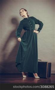Woman retro style long dark green gown with old suitcase, vintage photo