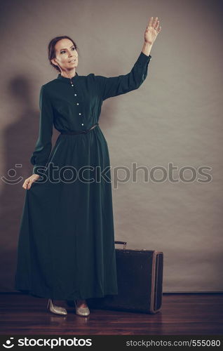 Woman retro style long dark green gown with old suitcase, vintage photo