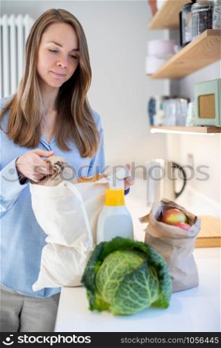 Woman Returning Home From Shopping Trip Unpacking Groceries In Plastic Free Bags