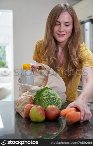 Woman Returning Home From Shopping Trip Unpacking Plastic Free Grocery Bags                                                              