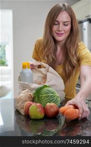 Woman Returning Home From Shopping Trip Unpacking Plastic Free Grocery Bags                                                              